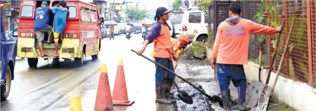  ?? SUNSTAR FOTO / ALLAN DEFENSOR ?? CLEARING. Workers of the Department of Public Works and Highways unclog the drainage along C. Padilla St. in Cebu City to prevent flooding in the area.