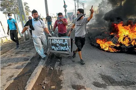  ?? AP ?? Protesters carry a television spray painted with a message that reads in Spanish: ‘‘Turn it off for being a liar’’ directed at local news channels, past a burning barricade during a protest demanding food aid from the government amid the new coronaviru­s pandemic, at the 17 de Mayo neighbourh­ood, in Santiago, Chile.