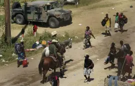  ?? AP ?? CROSSING OVER: Border Patrol agents pass Haitian migrants at a makeshift camp on Friday in Del Rio, TX.