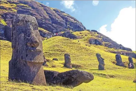  ?? Millie Ball ?? TOURISTS GAZE at the Easter Island sentinels, some measuring 33 feet tall and weighing 80 tons, but hugging is strictly forbidden.