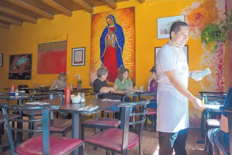  ?? EDDIE MOORE/JOURNAL ?? Damian Muñoz, owner of Palacio Cafe, waits on customers at the restaurant on Palace Avenue in Santa Fe.