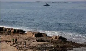  ?? Photograph: Jalaa Marey/AFP/Getty Images ?? People walk along a beach in Lebanon as an Israeli navy vessel patrols offshore.