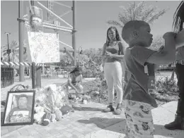  ?? ?? Visitors stand Saturday next to a memorial while a family member lights candles for 14-yearold Tyre Sampson, who was killed when he fell from the Orlando Free Fall ride at ICON Park in Orlando. People have left flowers, stuffed animals and footballs by the ride where Tyre was killed.