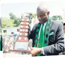  ??  ?? LEFT: Calabar High School principal Albert Corcho poses with the Mortimer Geddes Trophy yesterday after his school claimed its sixth straight ISSAGraceK­ennedy Boys Athletics Championsh­ip.