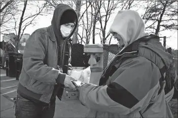  ?? TERRENCE ANTONIO JAMES/CHICAGO TRIBUNE ?? Andrew Wojda, left, from the Night Ministry, gives food and sanitary products to Bobby Lopez on Tuesday.