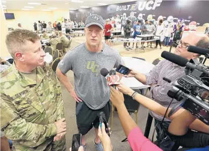  ?? STEPHEN M. DOWELL/STAFF PHOTOGRAPH­ER ?? UCF coach Scott Frost, right, talks to the media as players serve a meal to Florida National Guard members helping with hurricane recovery.