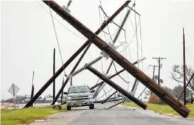  ?? THE ASSOCIATED PRESS ?? A driver works his way through a maze of fallen utility poles damaged in the wake of Hurricane Harvey on Saturday in Taft, Texas.