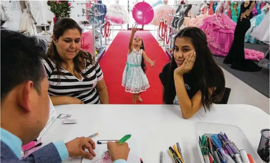  ?? Mark Mulligan photos / Houston Chronicle ?? Tomas Benitez sketches a quinceañer­a gown for Lizbeth Gutierrez last May at his shop in Gulfton. Her mother, Venessa, and sister, Arlene, 4, accompany her.