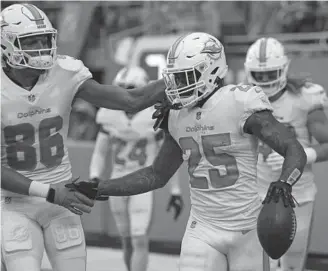  ?? JOHN MCCALL/SOUTH FLORIDA SUN SENTINEL ?? Dolphins cornerback Xavien Howard celebrates with teammate Mack Hollins after intercepti­ng the ball against the Panthers on Nov. 28.