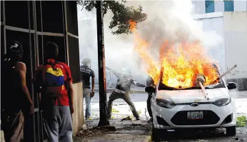  ?? — Reuters photo ?? Protesters are seen next to a burning car during a rally against Maduro’s government in Caracas,Venezuela.