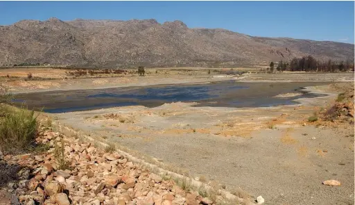  ??  ?? SCARCE: Low water level at a farm dam in the Koue Bokkeveld. The clarion call is to adapt to a changing climate and reduce the demand for water, the writer says.