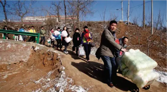  ??  ?? January 23, 2016: Volunteers from Shaanxi 1+1 Public Welfare Center send daily necessitie­s including quilts, food, and cooking oil to 17 impoverish­ed households in Lantian County, Shaanxi Province.