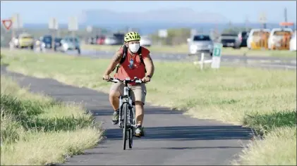  ?? The Maui News / MATTHEW THAYER photo ?? Ronnie Dizon of Wailuku gets some safe exercise while riding on the bike path along Maui Veterans Highway in Puunene on May 12. “I got bored at the house and was gaining weight,” Dizon said. He said the bike path had lately become a popular route for walkers and riders. As people across the U.S. turned to biking during the pandemic, some local shops have seen an increase in servicing and sales, though others are struggling to regain the business they lost when travel stopped.