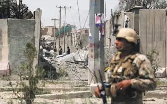  ?? AFP / Getty Images ?? An Afghan soldier stands guard at the site where a Taliban car bomb detonated at the entrance of a police station in Kabul, killing and wounding mostly women, children and other civilians.