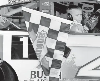  ?? SEAN GARDNER/ GETTY IMAGES ?? Keelan Harvick, son of Kevin Harvick, carries the checkered flag on his dad’s victory lap Sunday at Michigan Internatio­nal Speedway.