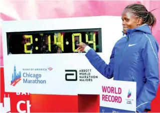  ??  ?? Brigid Kosgei of Kenya poses with her time after breaking the world record with a time of 2:14:04 during the Chicago Marathon yesterday.