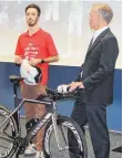  ?? FOTO: MARC DITTMANN ?? Patrick Reger, 70.3-Weltmeiste­r in der Altersklas­se 18 bis 24, erläutert Bernhard Göggel und den Zuhörern sein Fahrrad.