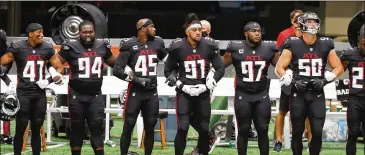  ?? CURTIS COMPTON / CURTIS.COMPTON@AJC.COM ?? Falcons players lock arms for the national anthem before Sunday’s game. Many players listed the name of a victim of social injustice or a phrase related to it on the bottom of their helmet.