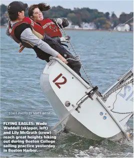  ?? StAffpHoto­byMAttWESt ?? FLYING EAGLES: Wade Waddell (skipper, left) and Lily McGrath (crew) reach great heights hiking out during Boston College sailing practice yesterday in Boston Harbor.