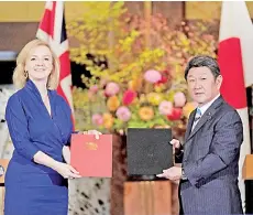  ?? — AFP photo ?? Truss (left) and Motegi exchange documents during a signing ceremony for economic partnershi­p between Japan and Britain at the Iikura Annex of the Foreign Ministry in Tokyo.