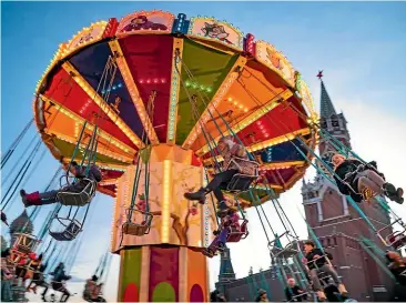  ??  ?? People ride a carousel in Red Square decorated for Christmas and New Year celebratio­ns. Moscow has seen unseasonab­ly warm weather this month, with no lasting snow cover.