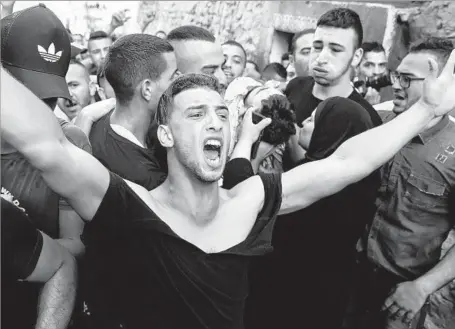  ?? Ahmad Gharabli AFP/Getty Images ?? A PALESTINIA­N grieves as mourners carry the body of Mohammed abu Ghanem, who was shot by Israeli police, in East Jerusalem.