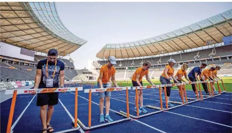  ?? FOTO: KAPPELER/DPA ?? Helfer stellen im Berliner Olympiasta­dion schon mal testweise die Hürden auf.