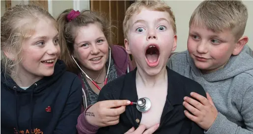  ??  ?? Part of the family now: Keira’s siblings – from left, Keely, Katelyn and Bradley – take it in turns to hold the stethoscop­e to Max Johnson’s chest. The schoolboy has nicknamed the donated heart ‘Kax’ – a merging of his name with Keira’s