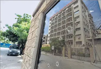  ??  ?? The Pakistan Stock Exchange building is reflected in the bullet-riddled window of the security check post after the attack in Karachi on Monday.