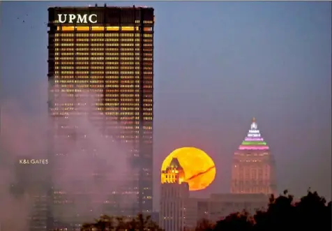  ?? Darrell Sapp ?? A super moon sets behind the Koppers Building, with the U.S. Steel Tower to the left and the Gulf Tower to the right, on Nov. 14, 2016, Downtown.