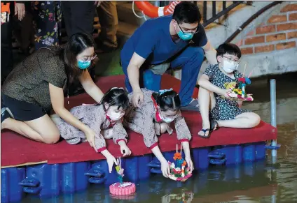  ?? ?? A Thai family places krathongs, small boats made of corn and decorated with banana leaves and flowers, into an Ong Ang canal Friday during the Loy Krathong festival.