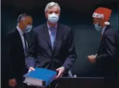  ?? OLIVIER HOSLET ?? A colleague wears a Christmas hat as European Union chief negotiator Michel Barnier, center, carries a binder of the Brexit trade deal during a special meeting at the European Council building in Brussels on Friday.
