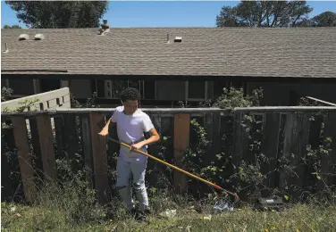  ??  ?? Joshua Owens, 14, rakes up trash outside his apartment building at Golden Gate Village in Marin City.