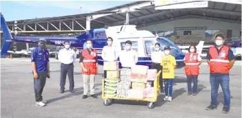  ??  ?? Shahdon (fifth from left), Fauziah (third from right), Remy (third from left) and the team involved in transporti­ng the food baskets in Pitas posing in front of the Layang-Layang helicopter and food that would be airlifted.