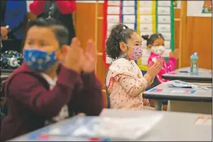  ?? (AP/Jae C. Hong) ?? First-graders applaud while listening to their teacher in a classroom on the first day of in-person learning at Heliotrope Avenue Elementary School in Maywood, Calif.