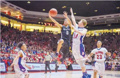  ?? ROBERTO E. ROSALES./JOURNAL ?? Volcano Vista’s Kyle Vargas, center, drives to the basket past Las Cruces’ Vincente Johnson, right, during the Class 6A boys state championsh­ip game at the Pit. The Hawks earned their first blue trophy with a 47-39 win.