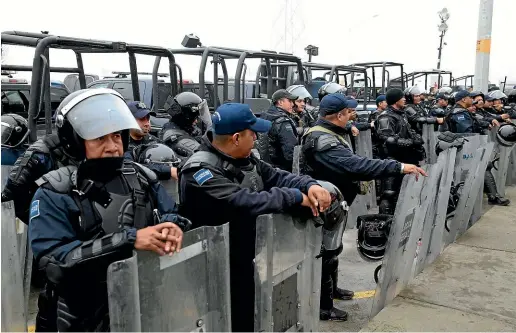  ?? AP ?? Mexican Federal Police in riot gear stand guard outside a migrant shelter for Central American immigrants in Piedras Negras.