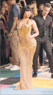  ?? Frazer Harrison Getty Images ?? NICKI MINAJ makes her grand entrance in a head-turning sheer gold beaded LaBourjois­ie gown cut to below the navel.