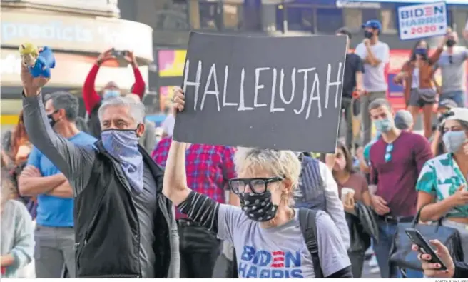  ?? PORTER BINKS / EFE ?? Una mujer levanta una pancarta en las calles de Nueva York durante una de las celebracio­nes espontánea­s que se registraro­n ayer tras conocerse la victoria de Joe Biden.