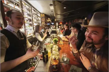  ?? PHOTOS BY DAMIAN DOVARGANES — THE ASSOCIATED PRESS ?? Seven Grand Bar Manager Evan Roth, left, talks to fellow bartender Roland Gonzalez, who tastes bourbon at the whiskey bar in Los Angeles on March 1. Seven Grand offers an extensive selection of over 700differe­nt whiskies.