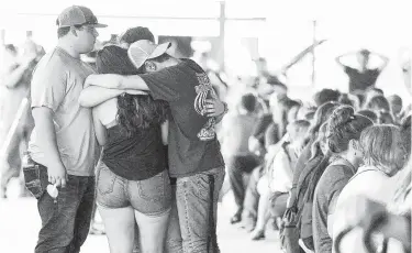  ??  ?? Attendees hug during a candleligh­t vigil on the first anniversar­y of the Santa Fe High School shooting. A day of activities was organized at the Galveston County fairground­s in Hitchcock.
