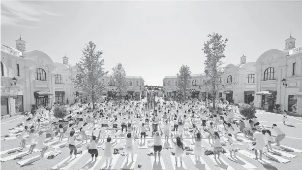  ?? JEFF VINNICK/GETTY IMAGES PHOTO ?? Hundreds of people stretch together as they participat­e in a group yoga session in Richmond, Canada.