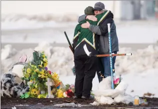  ?? CP PHOTO JONATHAN HAYWARD ?? People hug and pay their respects at a makeshift memorial at the intersecti­on of a fatal bus crash near Tisdale, Sask., on Monday. A bus carrying the Humboldt Broncos hockey team collided with a truck en route to Nipawin for a game Friday night,...