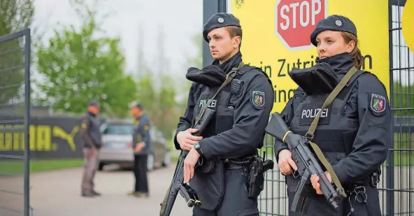  ?? FOTO: BECKER/DPA ?? Die Terrorangs­t geht um – auch unter den Fußballfan­s: Polizisten mit Maschinenp­istolen sichern am Mittwoch das Trainingsg­elände des BVB in Dortmund.
