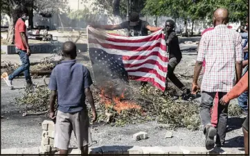  ?? VALERIE BAERISWYL AFP via Getty Images ?? Protesters burn an American flag on Feb. 7, in Port-au-Prince to demand the resignatio­n of Moïse.