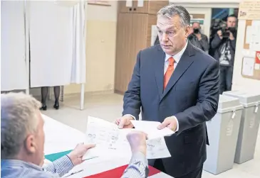  ?? BLOOMBERG ?? Viktor Orban receives his voting papers at a polling station yesterday during presidenti­al elections in Budapest, Hungary.