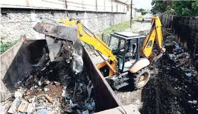  ?? PHOTOS BY RICARDO MAKYN/MULTIMEDIA PHOTO EDITOR ?? A tractor operator removes garbage from Stable Lane while the National Solid Waste Management Authority conducted a clean-up operation in the Fletcher’s Land community in KIngston, on Tuesday.