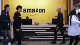  ?? ASSOCIATED PRESS FILE PHOTO ?? Employees walk through a lobby at Amazon’s headquarte­rs in Seattle.