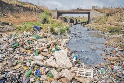  ?? Picture: Jacques Nelles ?? RIVER OF RUBBISH. A waste collector looks for recyclable­s along the polluted Hennops River near Olifantsfo­ntein recently. During heavy rains, enormous amounts of waste are swept downstream.