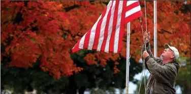  ?? File photo ?? Kenny Greer, cemetery manager, raises an American flag, with a backdrop of red fall leaves, last year near the entrance at the Benton County Memorial Park in Rogers. Northwest Arkansas boasts many locations for beautiful fall leaf color.
